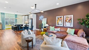 A modern living room with a sofa, armchairs, a coffee table, and a dining area with a kitchen in the background.