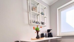 A modern kitchen with a white countertop, a built-in shelf, a coffee machine, and a vase with tulips. - Modern vacation home with terrace in a quiet cul-de-sac in beautiful Aurich (Aurich)