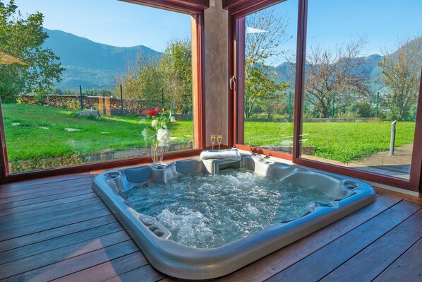 A hot tub on a wooden deck with a view of a grassy area and mountains. - AlpiZen centre de Ressourcement - Adults recommended (Coise-Saint-Jean-Pied-Gauthier)