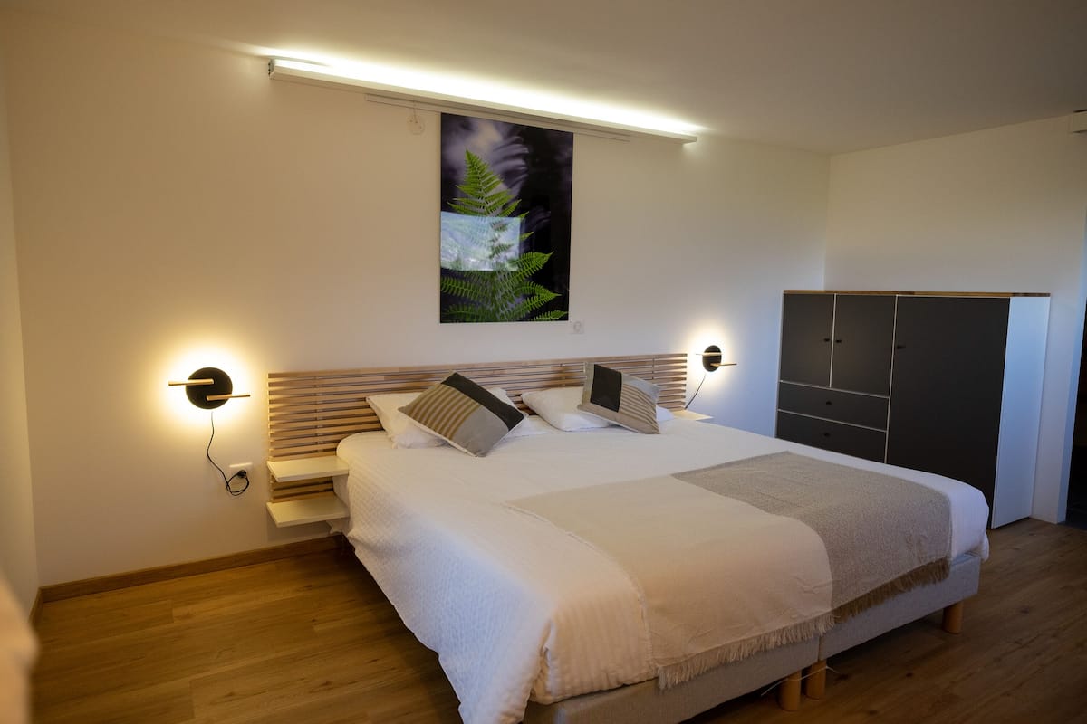 Un dormitorio con cama, mesitas de noche, armario y una obra de arte colgada en la pared.