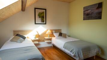 Una habitación con dos camas, cabeceros de madera, un cuadro en la pared y una lámpara en la mesita de noche.