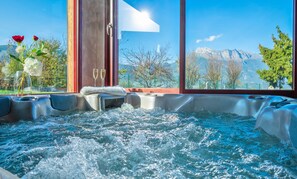A hot tub with a mountain view, a vase with flowers, and two glasses of champagne. - AlpiZen centre de Ressourcement - Adults recommended (Coise-Saint-Jean-Pied-Gauthier)