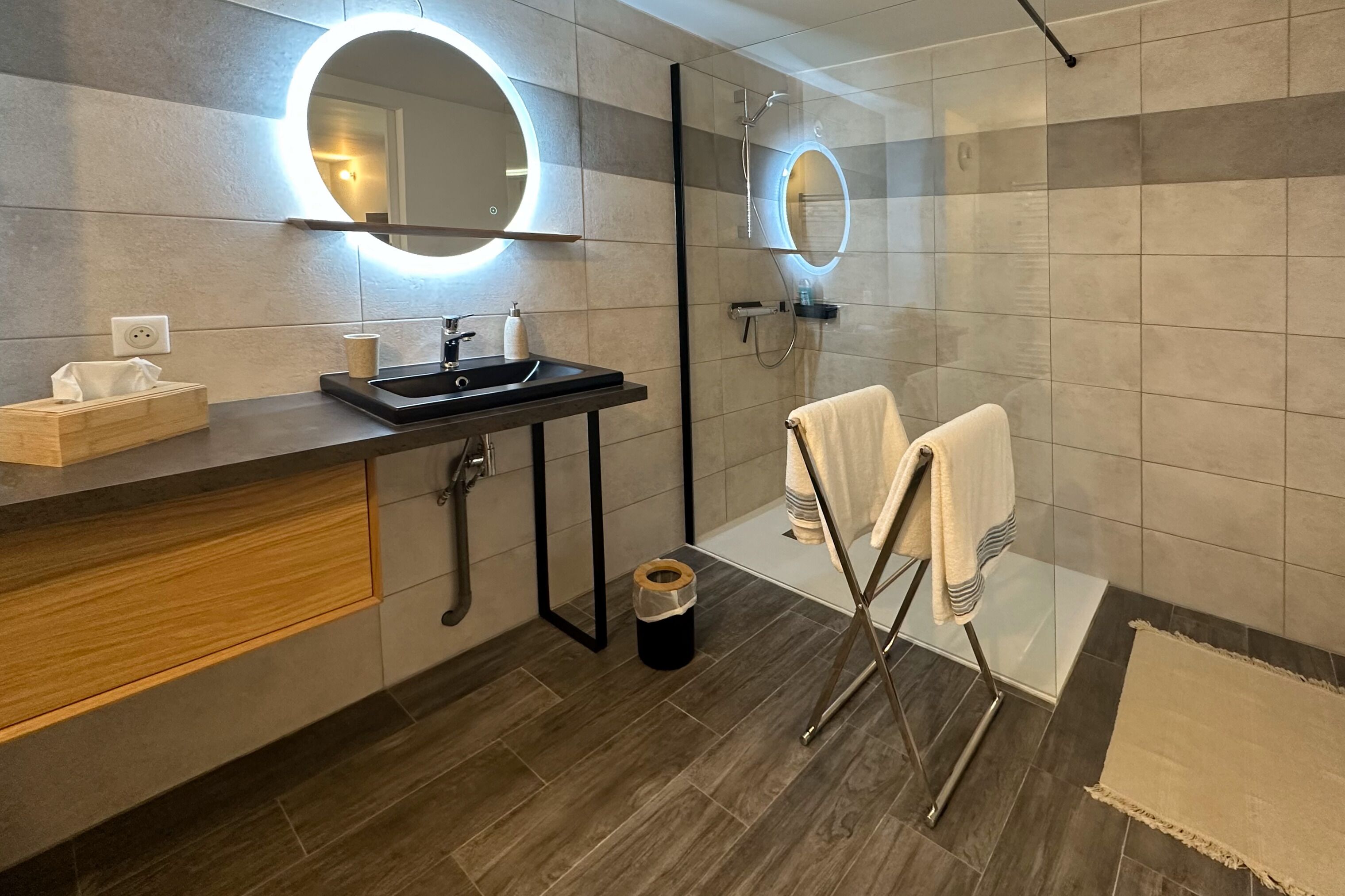 A modern bathroom with a sink, mirror, and shower.