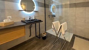 A modern bathroom with a sink, mirror, and shower.