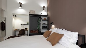 A modern hotel room with a large bed, a desk, a chair, a wardrobe, and a mirror. - Style & Stone Guest House (Rome)