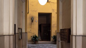 A hallway with a patterned floor, a hanging light fixture, and a door at the end. - Style & Stone Guest House (Rome)