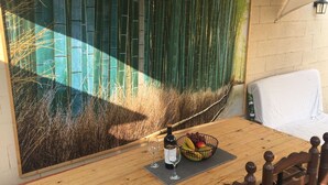 A wooden table with a glass of wine and a fruit bowl, set against a bamboo wall. - Villa Garden, Pool & sea (El Campello)