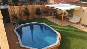 A backyard with a swimming pool, artificial grass, a wooden deck, and a patio area with a table and chairs. - Villa Garden, Pool & sea (El Campello)