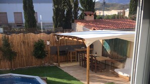 A backyard with a swimming pool, wooden deck, and a covered patio area. - Villa Garden, Pool & sea (El Campello)