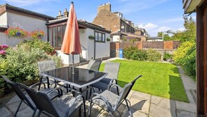 A patio with a table and chairs, a glass-top table, and a single umbrella.