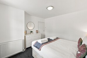 Un dormitorio con cama, cómoda y espejo redondo.