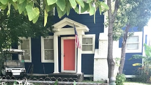 A house with a red door, an American flag, and a golf cart parked in front.