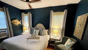 A bedroom with a bed, bedside tables, a chair, and a ceiling fan.