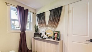 A room with a window, a radiator, a mirror, and a small table with a radio and a picture frame. - The Emerald Haus: Stylish Retreat Near Regis (Denver)