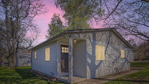 A small, single-story building with a door and windows, surrounded by grass and trees. - The Emerald Haus: Stylish Retreat Near Regis (Denver)