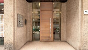 A hotel entrance with a wooden door, a glass panel, and a small step leading up to the door.