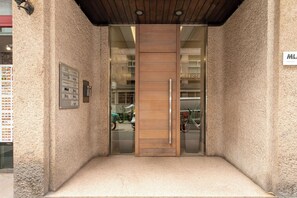 A hotel entrance with a wooden door, a glass panel, and a small step leading up to the door.