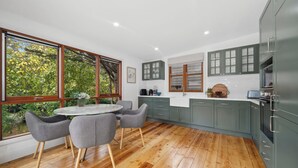 A modern kitchen with wooden flooring, grey cabinets, and a round dining table with chairs. - Bisham Cottage
Fully renovated two bedroom Cottage with a brand new out door Spa (Katoomba)