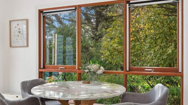 A dining area with a round table, grey chairs, and a window with a view of greenery. - Bisham Cottage
Fully renovated two bedroom Cottage with a brand new out door Spa (Katoomba)