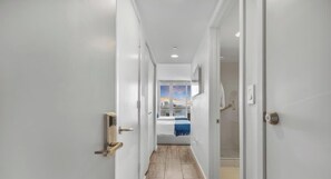 A hallway leading to a bedroom with a bed, a view of the sky, and a door with a lock. - Studio + Balcony with stunning views - Near Beach (Hallandale Beach)