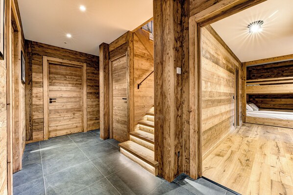 A wooden interior with a staircase, a door, and a bed.