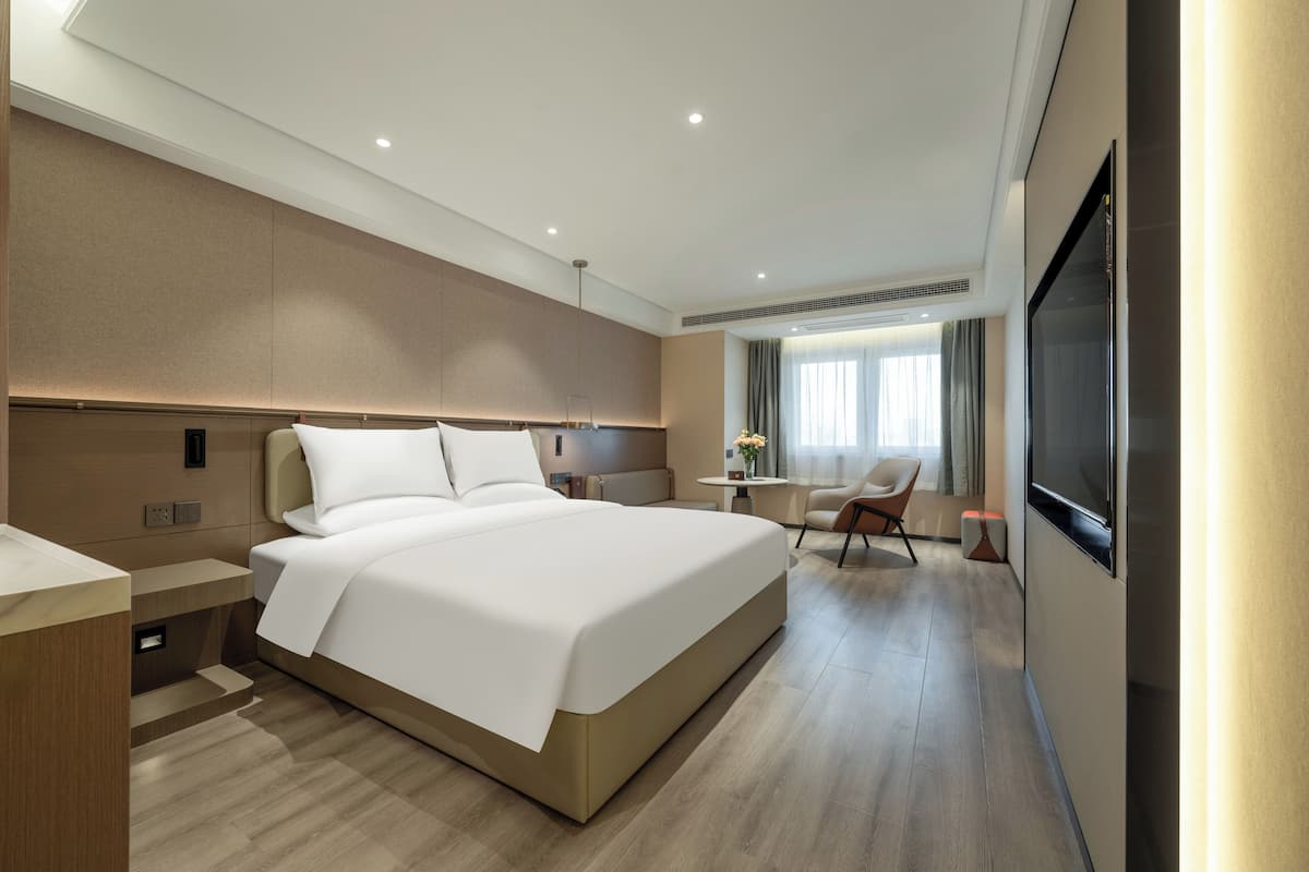 Ett modernt hotellrum med en stor säng, ett skrivbord, en stol och en TV.