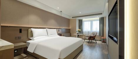 A modern hotel room with a large bed, a desk, a chair, and a TV.