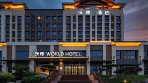 A modern hotel with a prominent entrance, multiple floors, and a well-lit facade. - World Hotel Jinan Wenlvcheng Branch (Jinan)