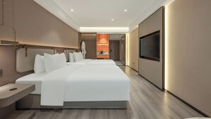 Una habitación de hotel moderna con una cama grande, mesitas de noche, un televisor y una pequeña cocina.