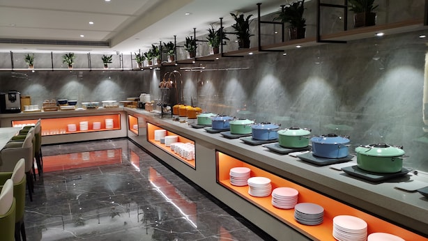 A modern hotel lobby with a marble floor, a reception desk, and a buffet area with various dishes and plates. - World Hotel Jinan Wenlvcheng Branch (Jinan)