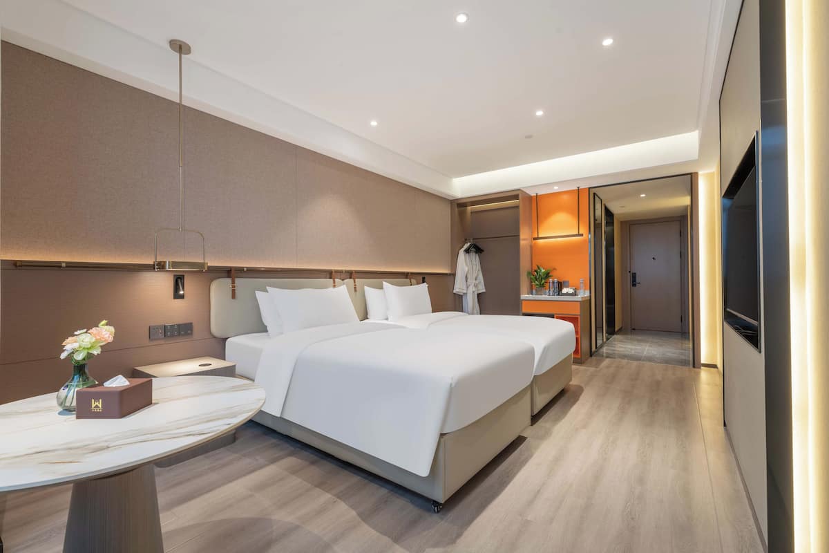 Ett modernt hotellrum med en stor säng, sängbord, ett skrivbord och ett litet badrum.