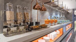 Zona de bufé con varios recipientes de comida y utensilios.
