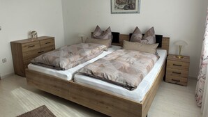 Un lit double avec un cadre en bois, deux tables de chevet, une petite table, une lampe et un tableau encadré au mur.