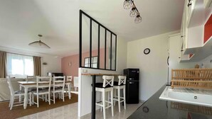 Una cocina moderna con encimera negra, armarios blancos y un comedor con sillas y mesa blancos.