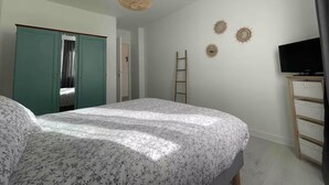 Un dormitorio con cama, armario, televisor y decoración en la pared.