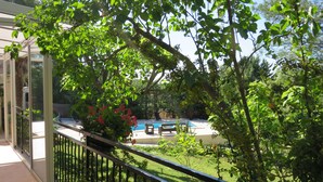 A pool area with a view of a garden and a building with a balcony.