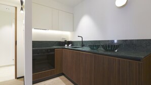 Een moderne keuken met houten kastjes, een zwart aanrecht en een ingebouwde oven.