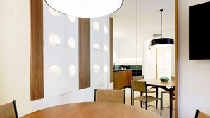 Een moderne eetruimte met een ronde houten tafel, stoelen en een hanglamp.