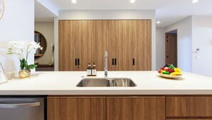 Una cocina moderna con una isla central, armarios de madera y un lavamanos de acero inoxidable.