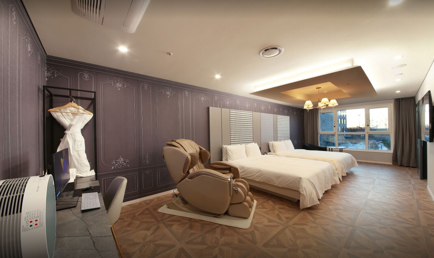 A hotel room with a massage chair, two beds, a large window with a view, and a modern design.