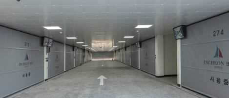 A hallway with numbered doors, directional arrows, and a surveillance camera.