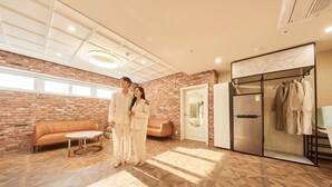 A room with a brick wall, a sofa, a table, a wardrobe, and a door. - Restia Incheonbay Hotel (Incheon)