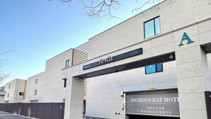 A hotel entrance with a sign reading "Resstia Incheon Bay Hotel" and a parking area with directional arrows. - Restia Incheonbay Hotel (Incheon)