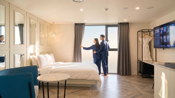 A hotel room with a bed, a round table, a TV, and a large window with curtains. - Restia Incheonbay Hotel (Incheon)