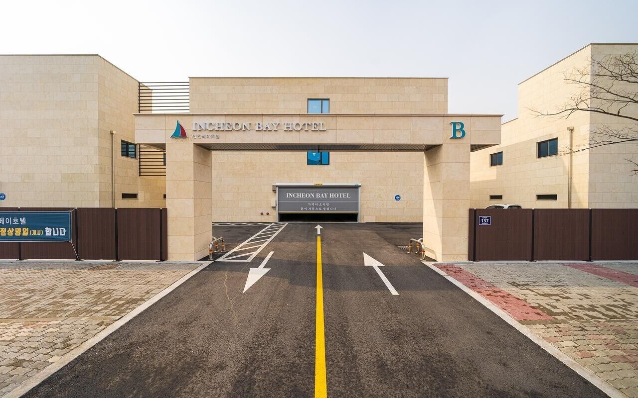 La entrada al Incheon Bay Hotel, con un camino despejado señalizado con flechas que guían hacia la entrada.