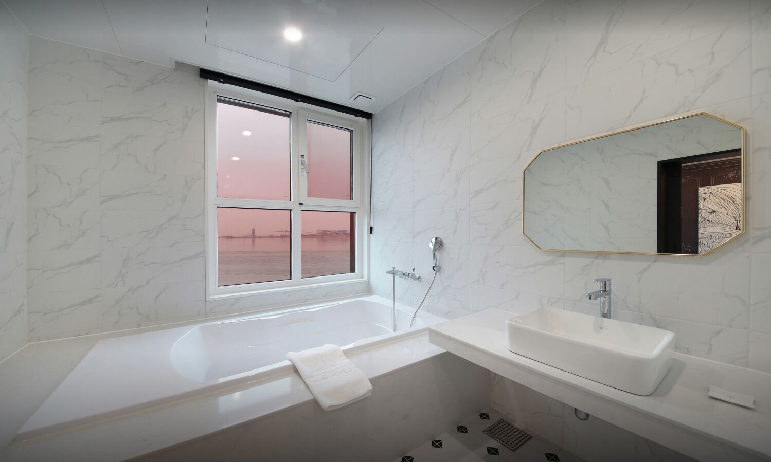 Un baño moderno con bañera, lavamanos y ventana con vidrio esmerilado.