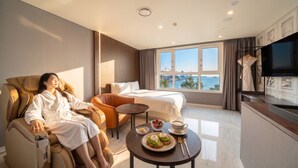 A hotel room with a massage chair, a bed, a dining table with breakfast, and a large window with a view of the sea. - Restia Incheonbay Hotel (Incheon)