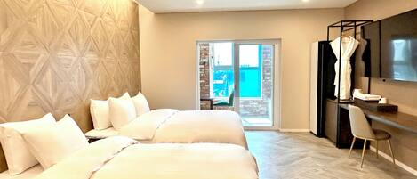 A hotel room with two beds, a desk, a chair, a TV, and a balcony with a view.