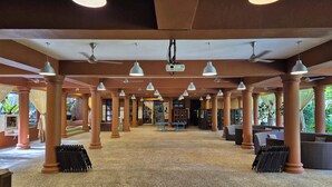 A spacious indoor area with columns, ceiling fans, and hanging lights.
