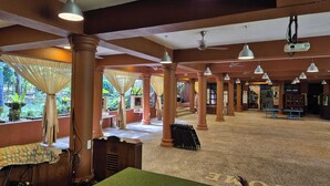 A spacious indoor area with multiple columns, ceiling fans, and hanging lights.